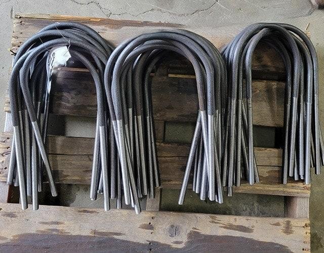 Bundles of custom U-bolts with threaded ends stacked on a wooden pallet, manufactured by Valley Nut & Bolt